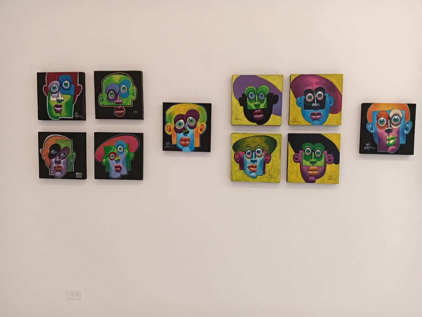 Wall of Puzzle paintings hung in two groups
