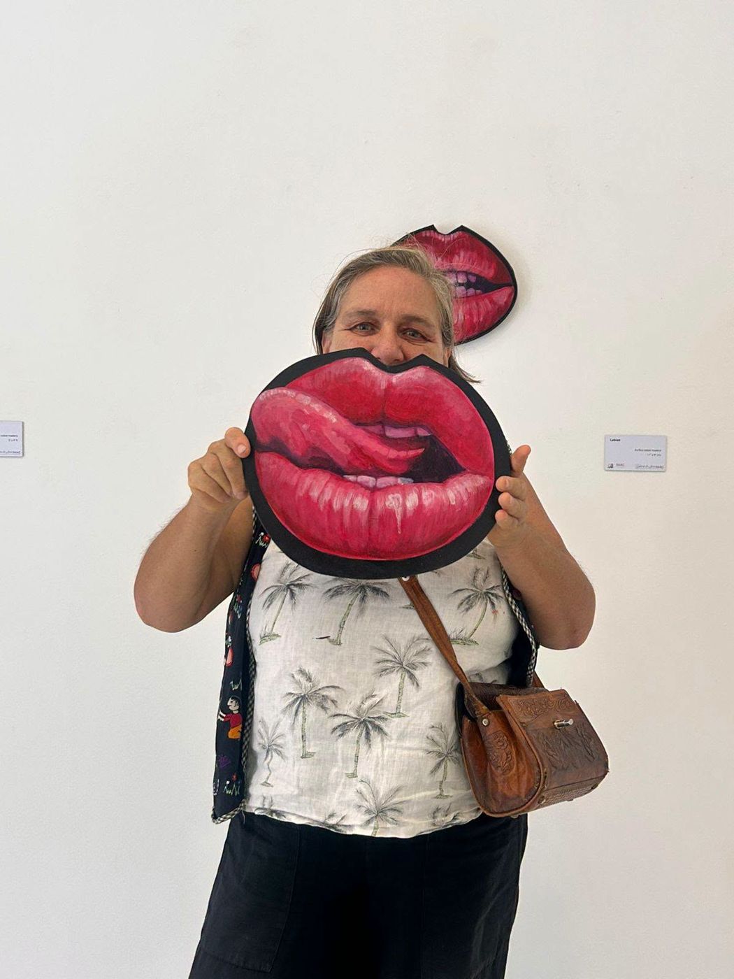 Rocío Hoffmann holding a painted pair of lips in front of her face
