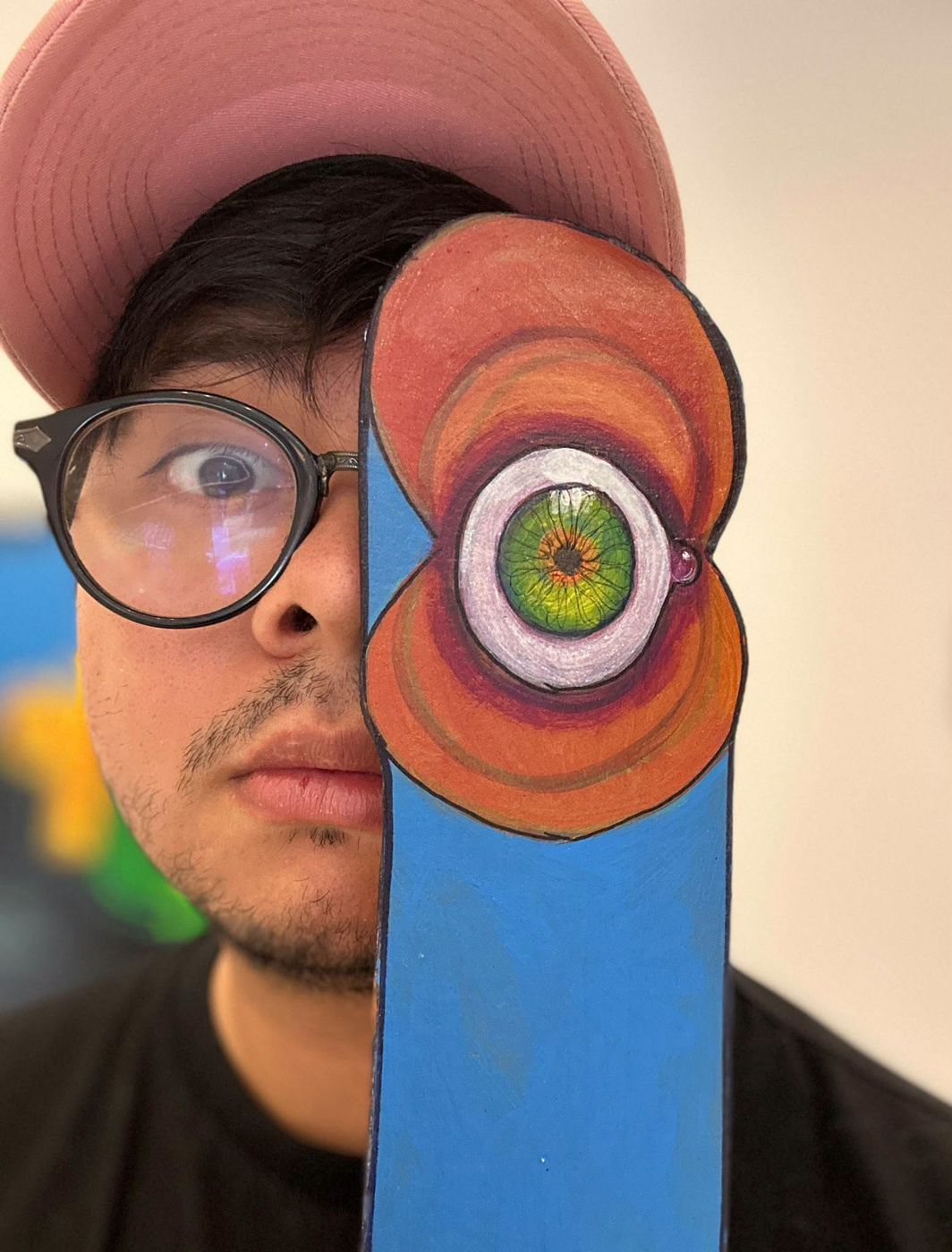 A visitor in glasses holding a Puzzle eye piece over half his face
