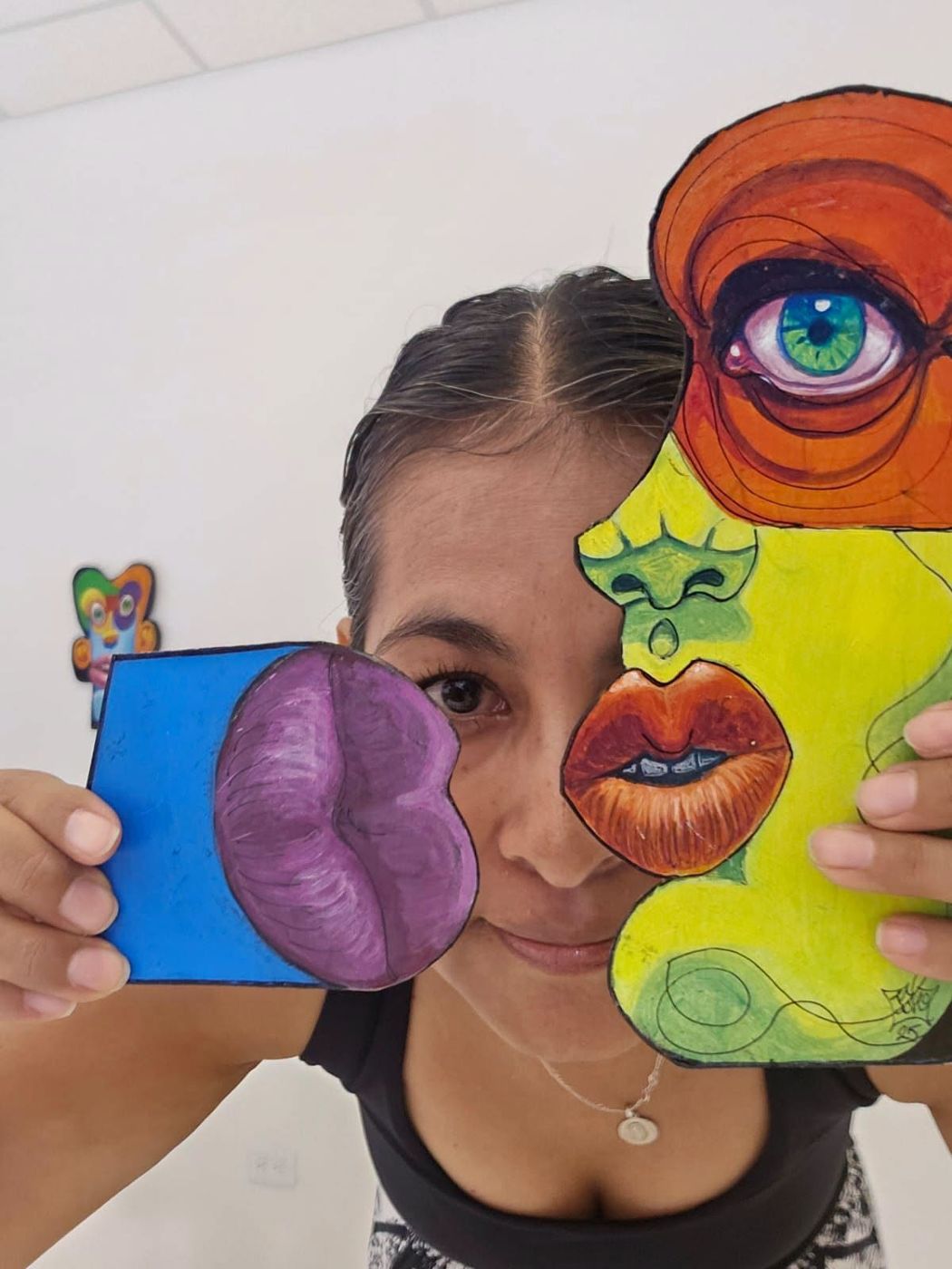 A visitor holding two Puzzle pieces, a purple mouth and a yellow face, over her face