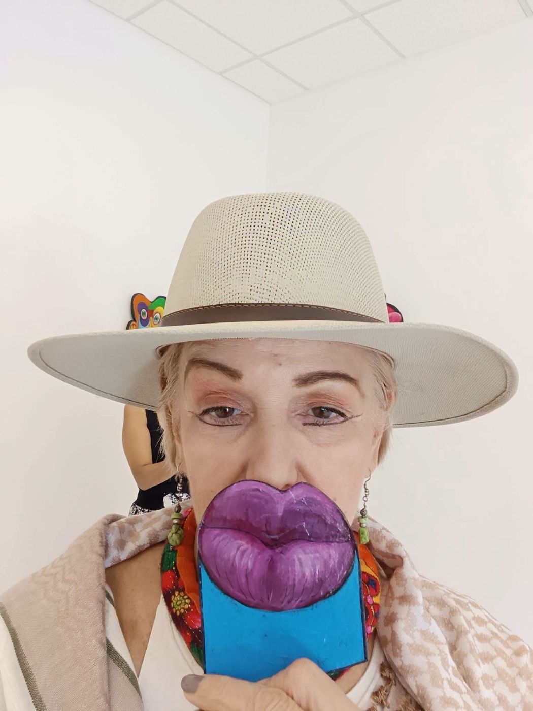 A visitor in a white hat holding a purple lips piece in front of her mouth