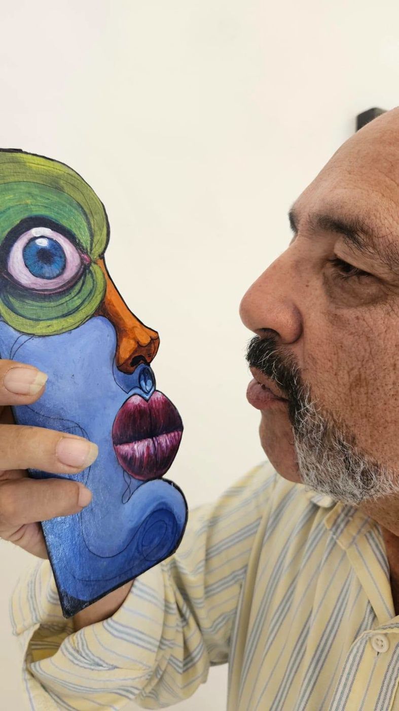 A visitor holding a tall Puzzle face piece beside his own face