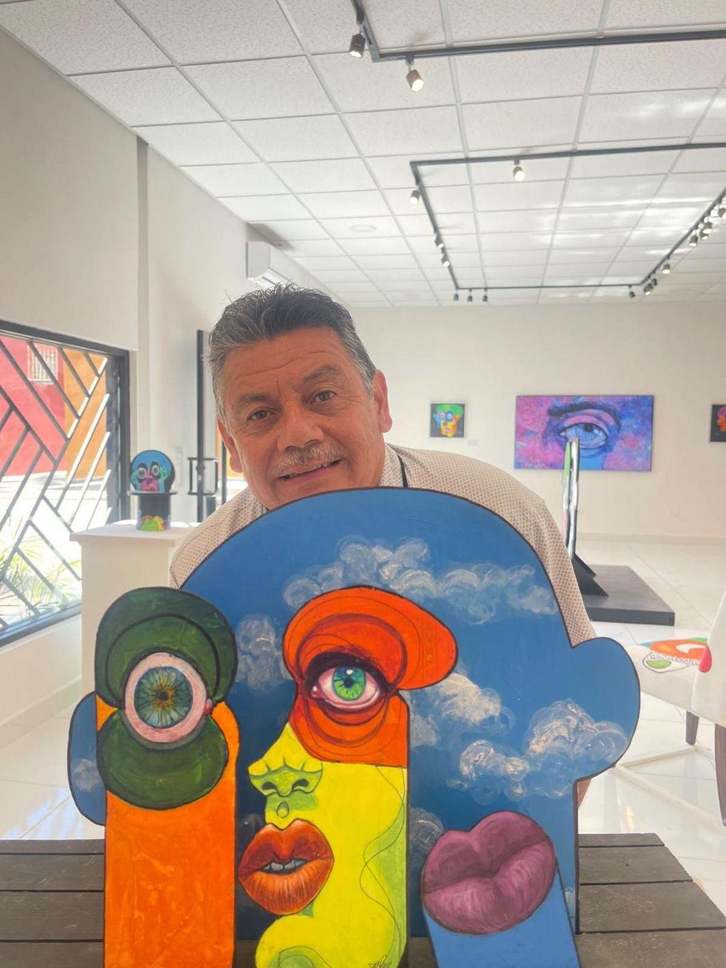A visitor seated behind a Puzzle art object with a painted sky