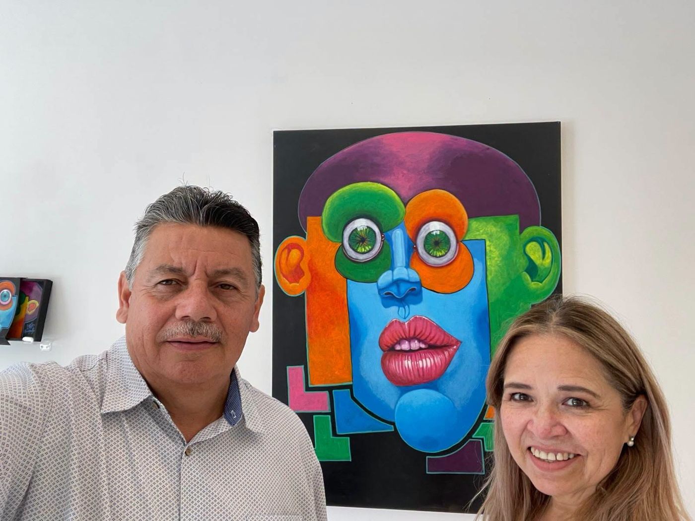 Two visitors taking a photo in front of a large Puzzle painting