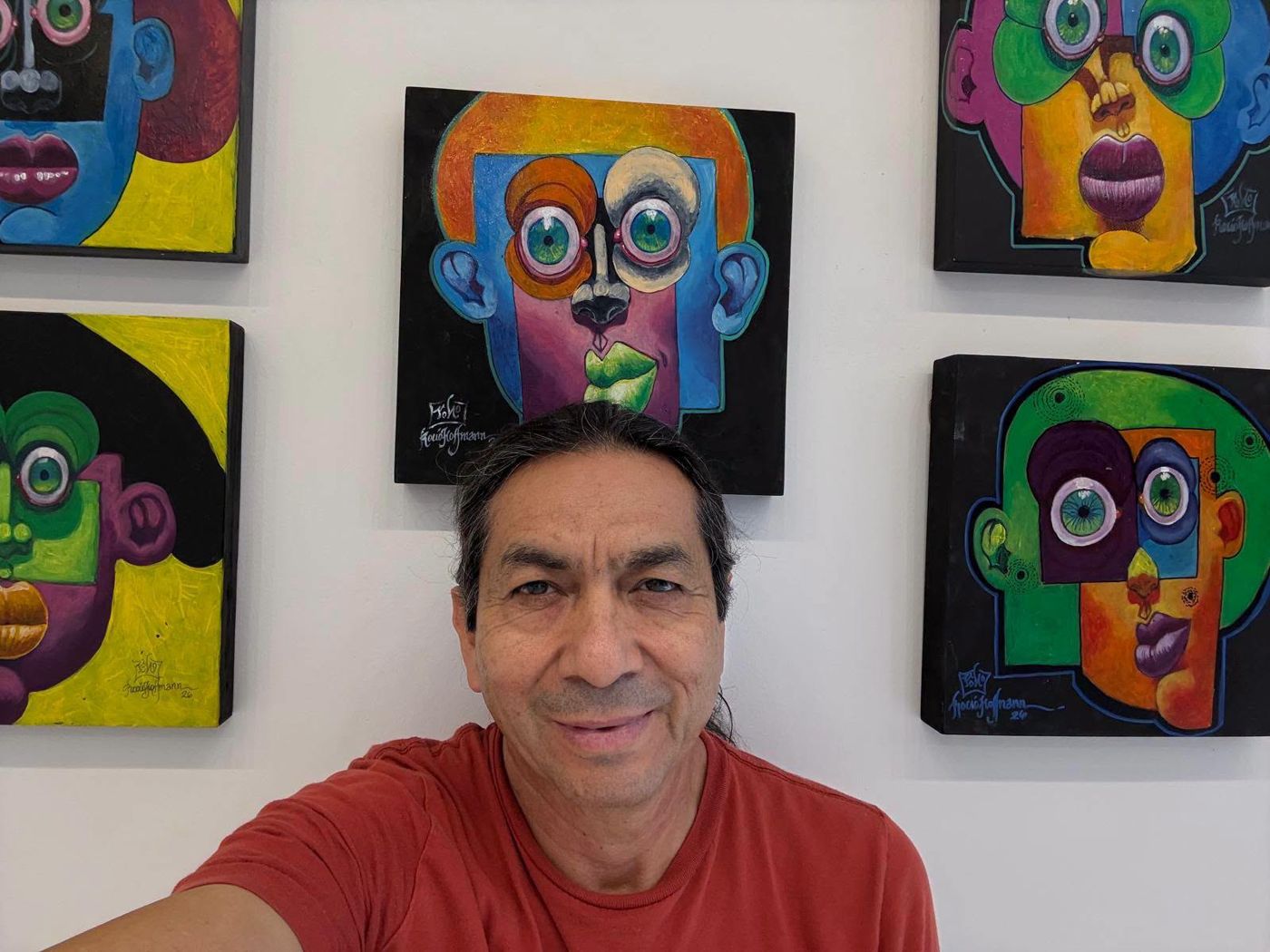 A visitor taking a selfie in front of a wall of Puzzle paintings