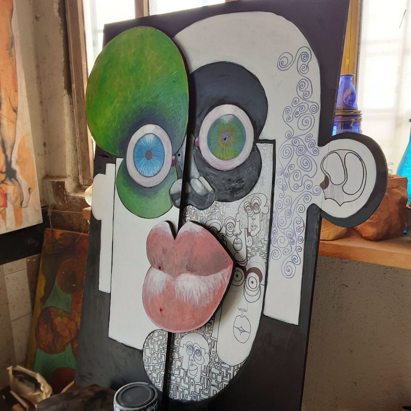Puzzle art object: a tall cut-out face in green, white and grey with pink lips