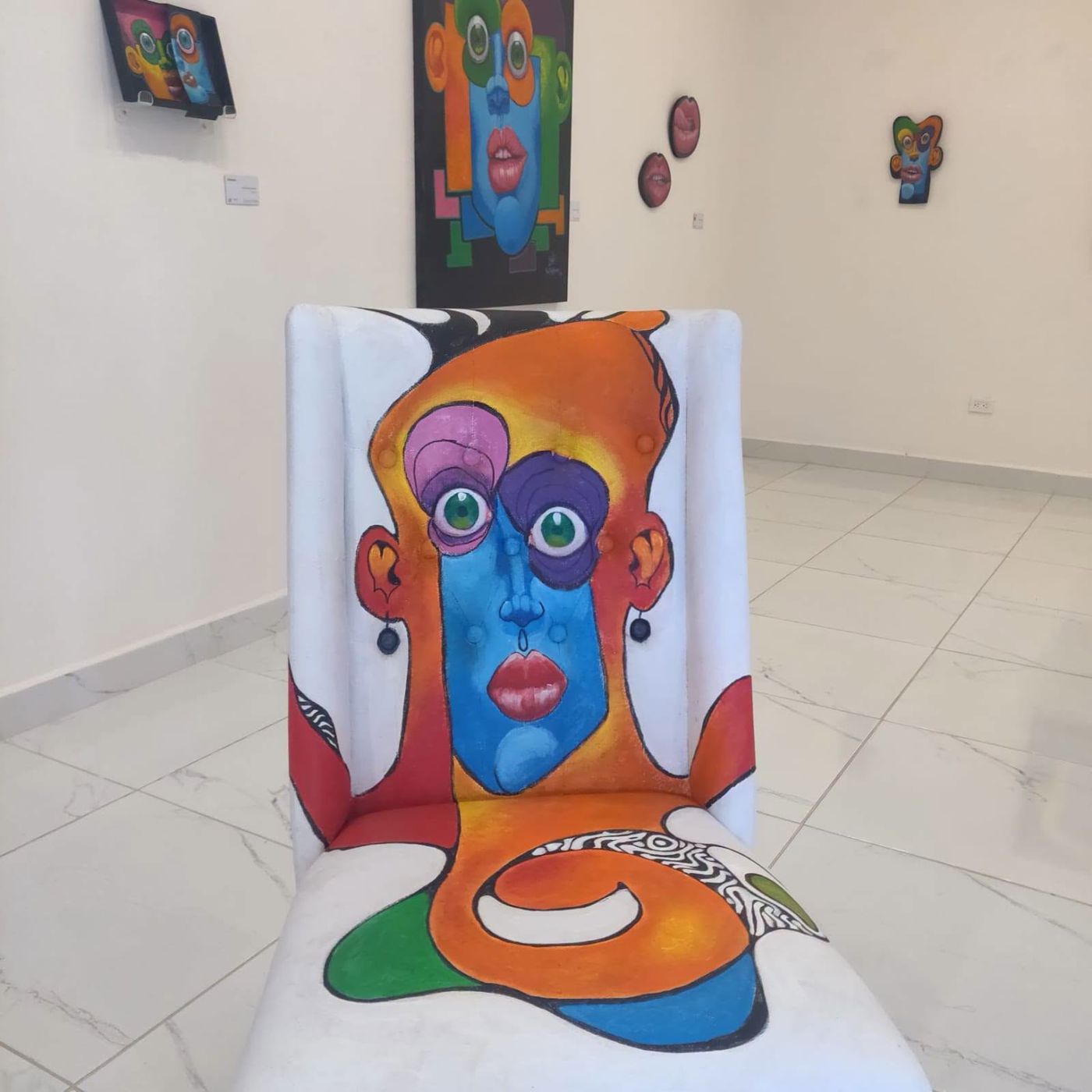White chair painted with an orange and blue Puzzle face, in the gallery