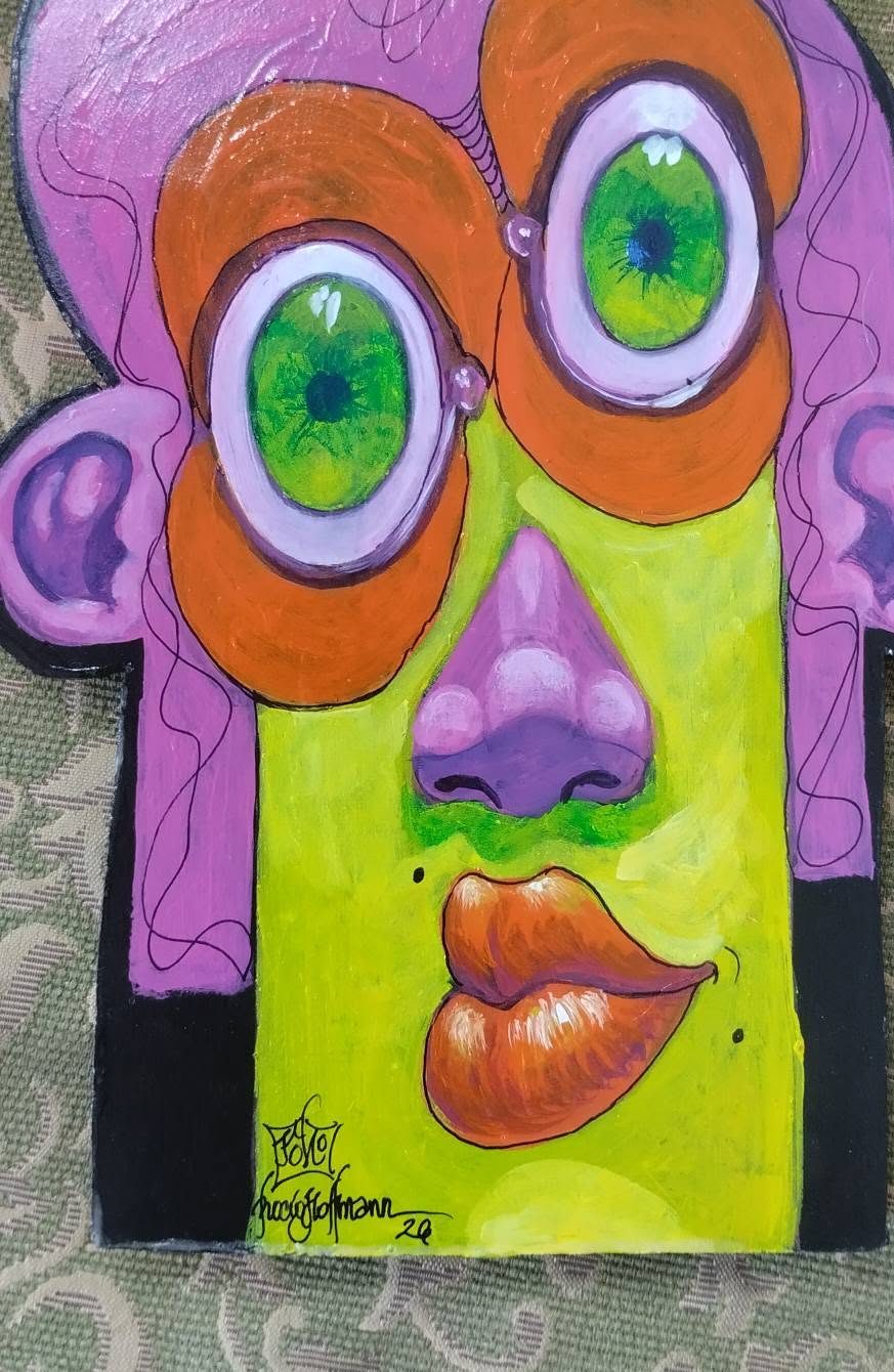 Cut-out Puzzle piece: a lime-green face with pink hair, orange circles around green eyes and orange lips