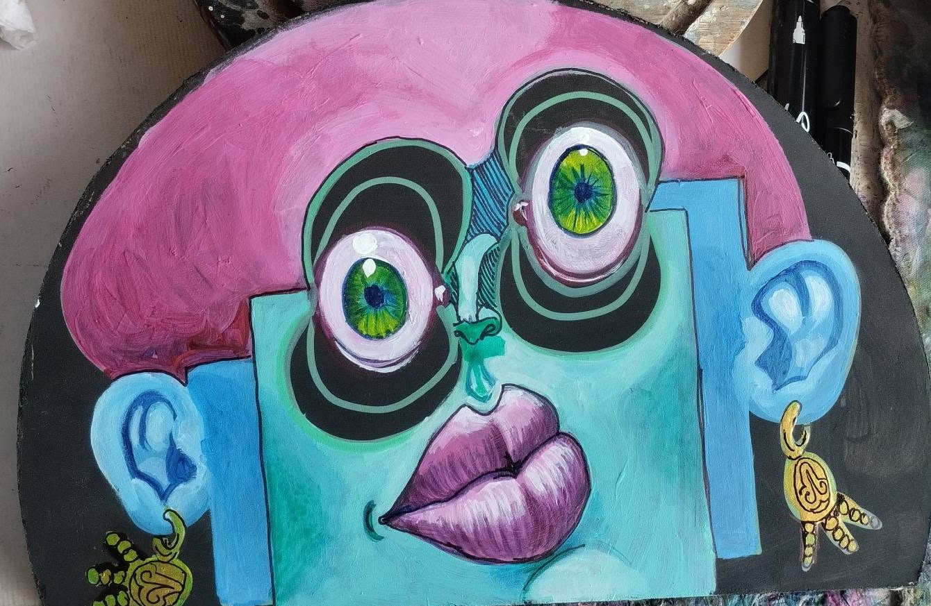 Half-moon Puzzle piece: a turquoise face with pink hair, green eyes and gold earrings