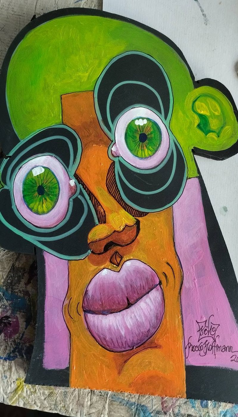 Cut-out Puzzle piece: a green and orange face with black and mint circles around green eyes